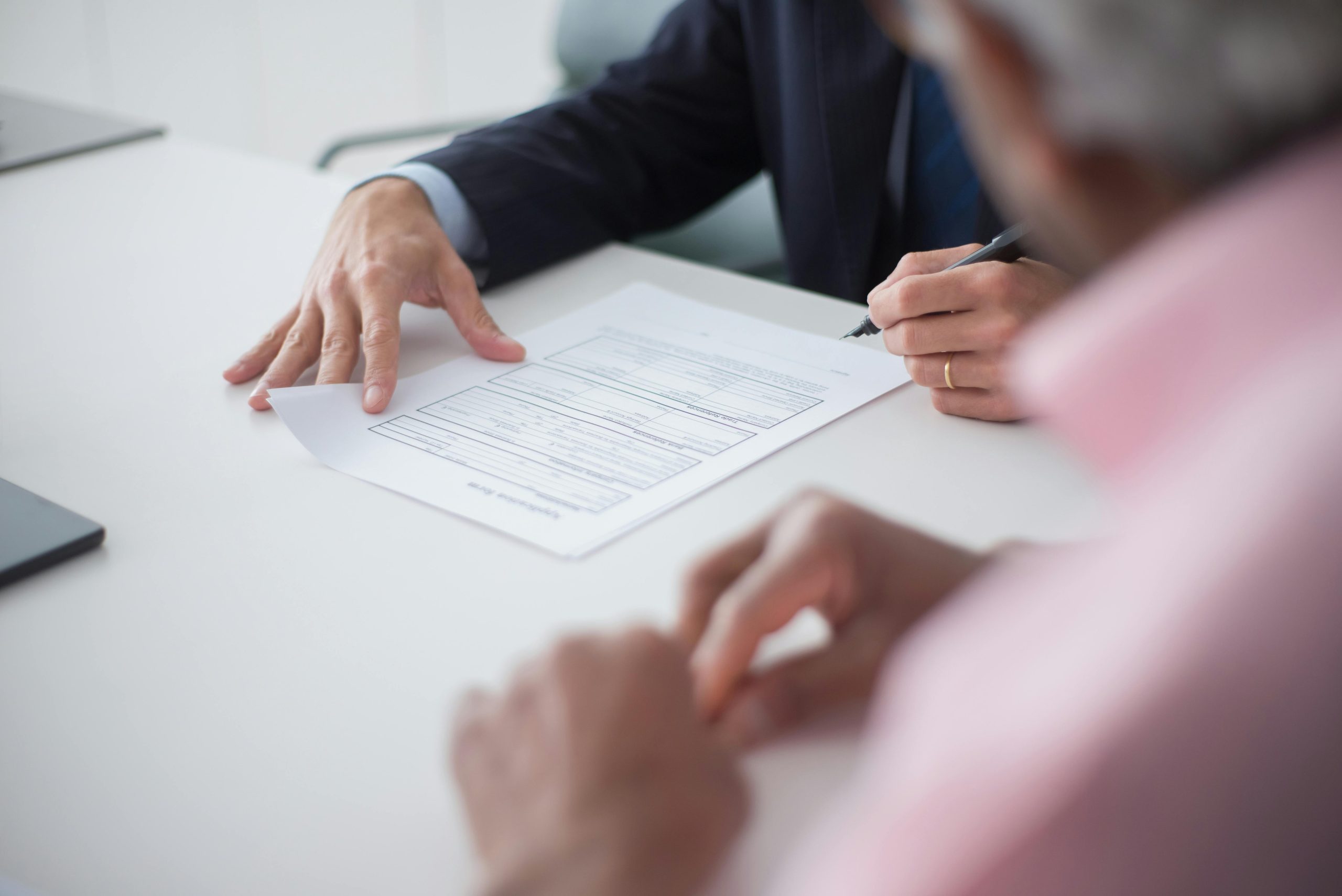 alt="Two professionals engaging in a business meeting, signing documents for a consulting agreement."
